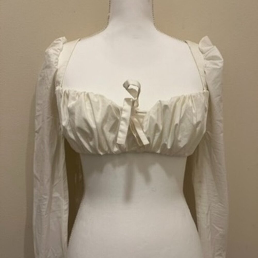 A white crop top with a low neck line, a central bonding detail for structure.
